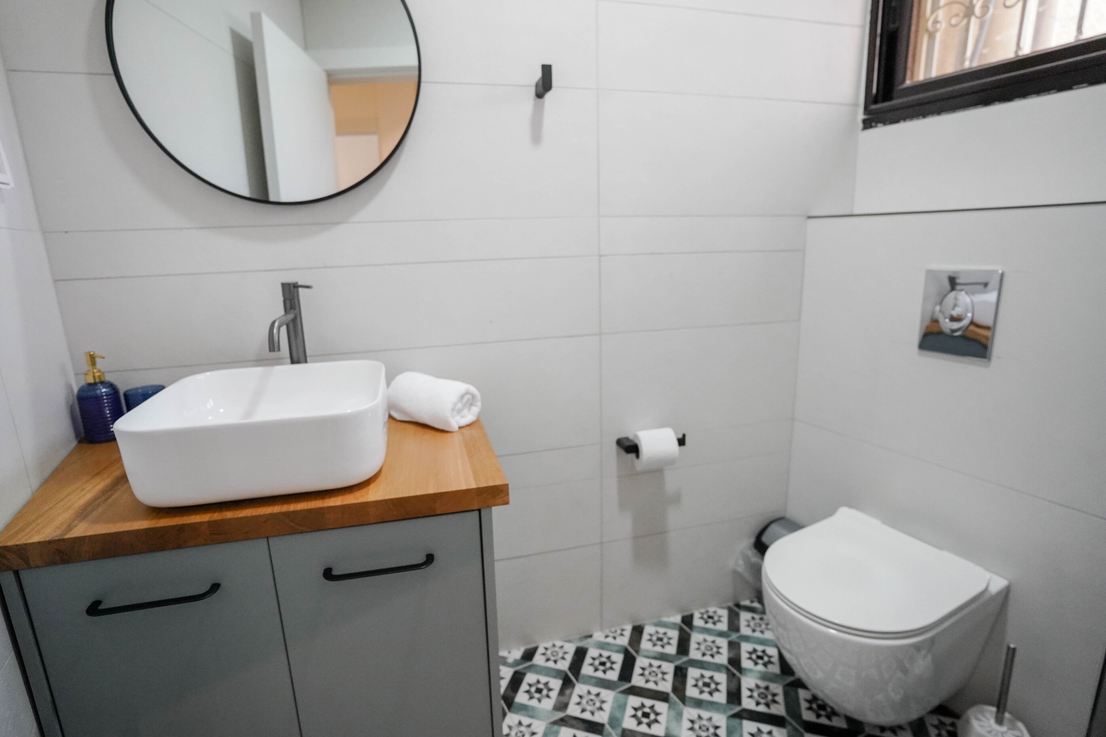 Une salle de bain avec un lavabo blanc, un plan de toilette en bois et des toilettes.