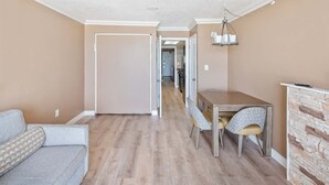 Una sala de estar moderna con un sofá gris, una mesa de comedor con sillas y una chimenea de piedra.