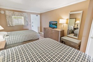 A hotel room with two beds, a TV, a mirror, and a dresser.