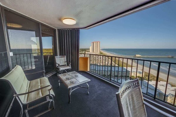 Un balcon avec vue sur la plage et l’océan, aménagé avec un canapé et une table.