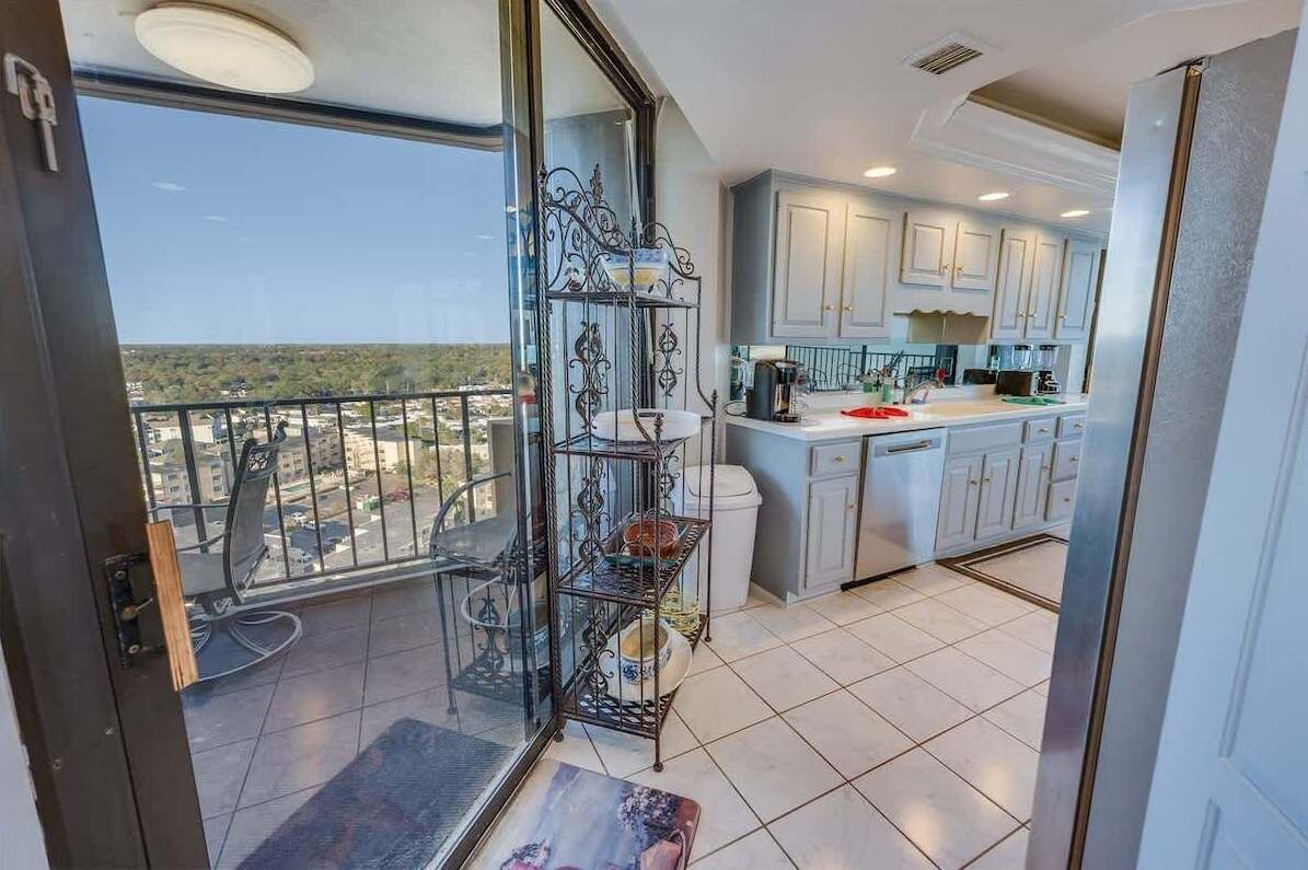 Una cocina moderna con armarios blancos y un balcón con puerta de vidrio.