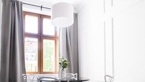 Een moderne eethoek met een ronde tafel, witte stoelen en een hangende lamp.