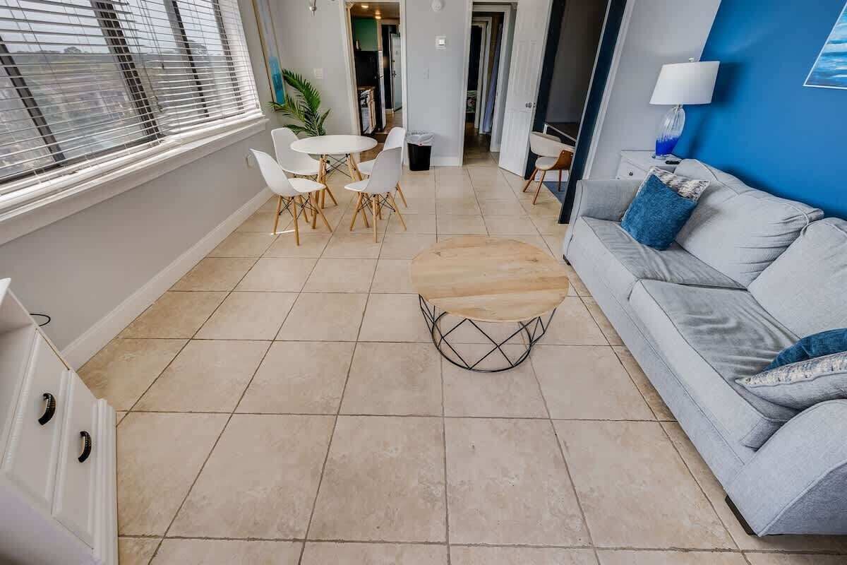 Un salon moderne avec un canapé gris, une table basse ronde et un coin repas comprenant des chaises blanches et une petite table.