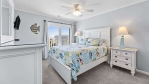A bedroom with a bed, a nightstand, a ceiling fan, a window, and a fish decoration on the wall.
