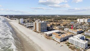 A coastal hotel area with beachfront properties, including high-rise and low-rise buildings, and a visible road.