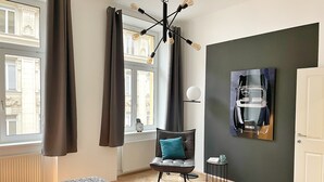Moderni hotellihuone, jossa on sänky, tuoli, pieni pöytä ja taulu seinällä.
