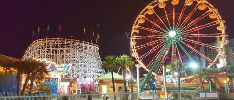 A Ferris wheel and a roller coaster at a nighttime amusement park.