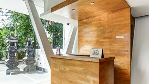 A reception desk with a wooden finish, a small calendar, and a sign indicating a no-smoking area. - Collection O Legian Near Pantai Kuta Formerly Premium Legian (Legian)