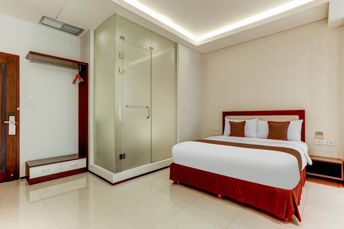 Habitació d'hotel amb llit, vestidor i dutxa.