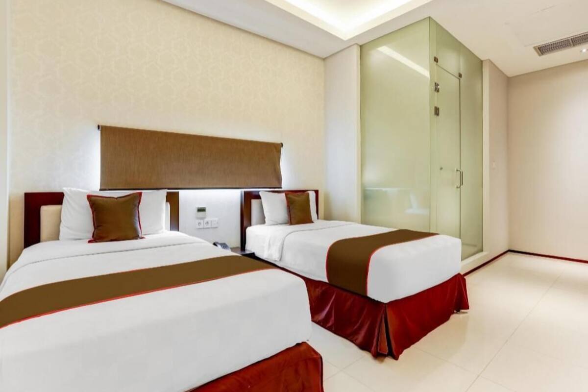 Habitació d'hotel amb dos llits, un armari de vidre i un disseny modern.