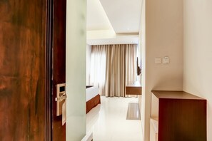 A hotel room with a bed, a bedside table, a mirror, and a window with curtains. - Collection O Legian Near Pantai Kuta Formerly Premium Legian (Legian)
