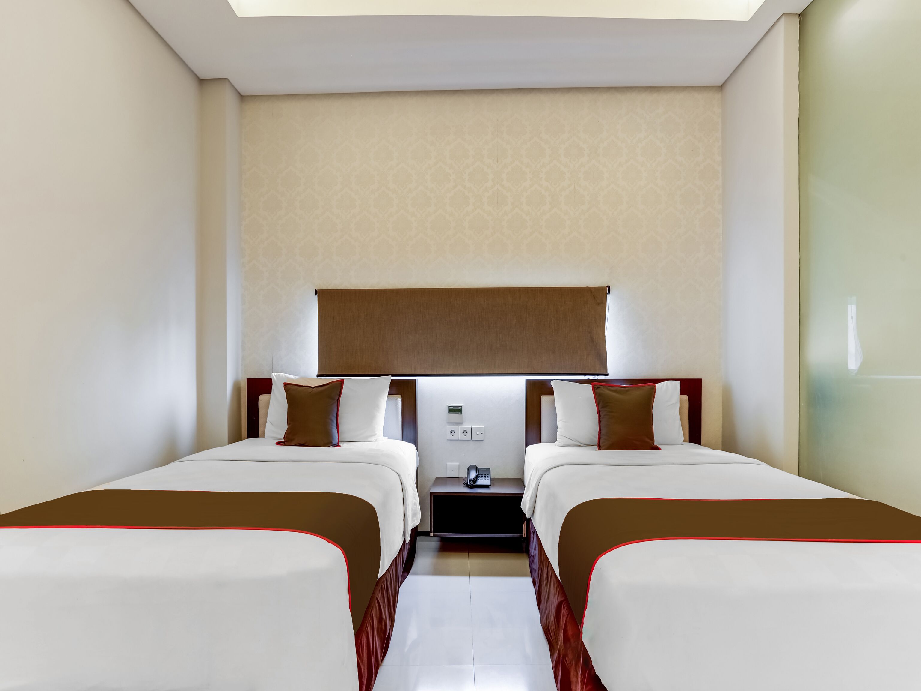 Ein Hotelzimmer mit zwei Betten, einem Nachttisch, einem Telefon und einem Fenster mit Blick.
