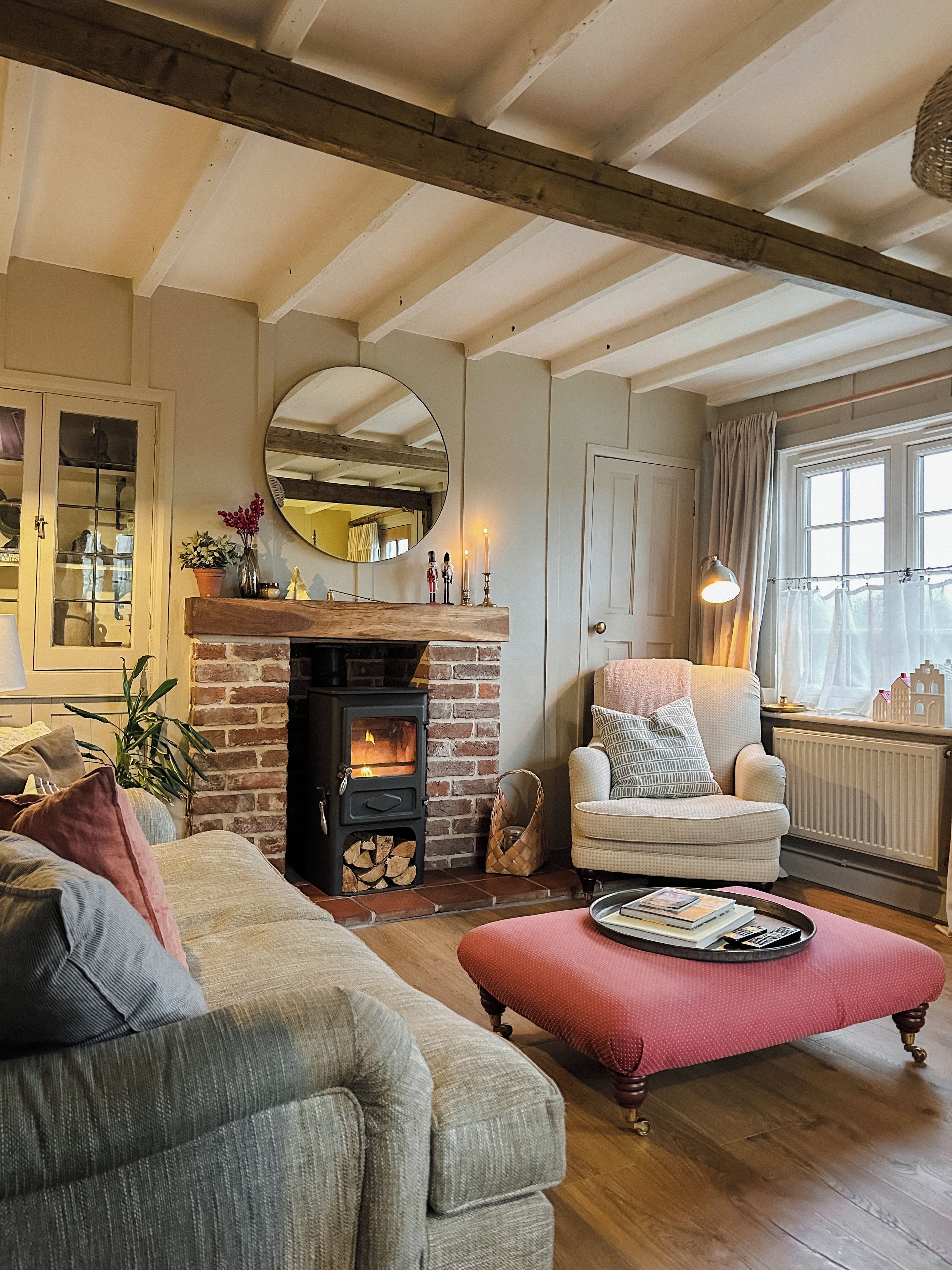 A cozy living room with a fireplace, a comfortable armchair, a sofa, and a wooden floor.