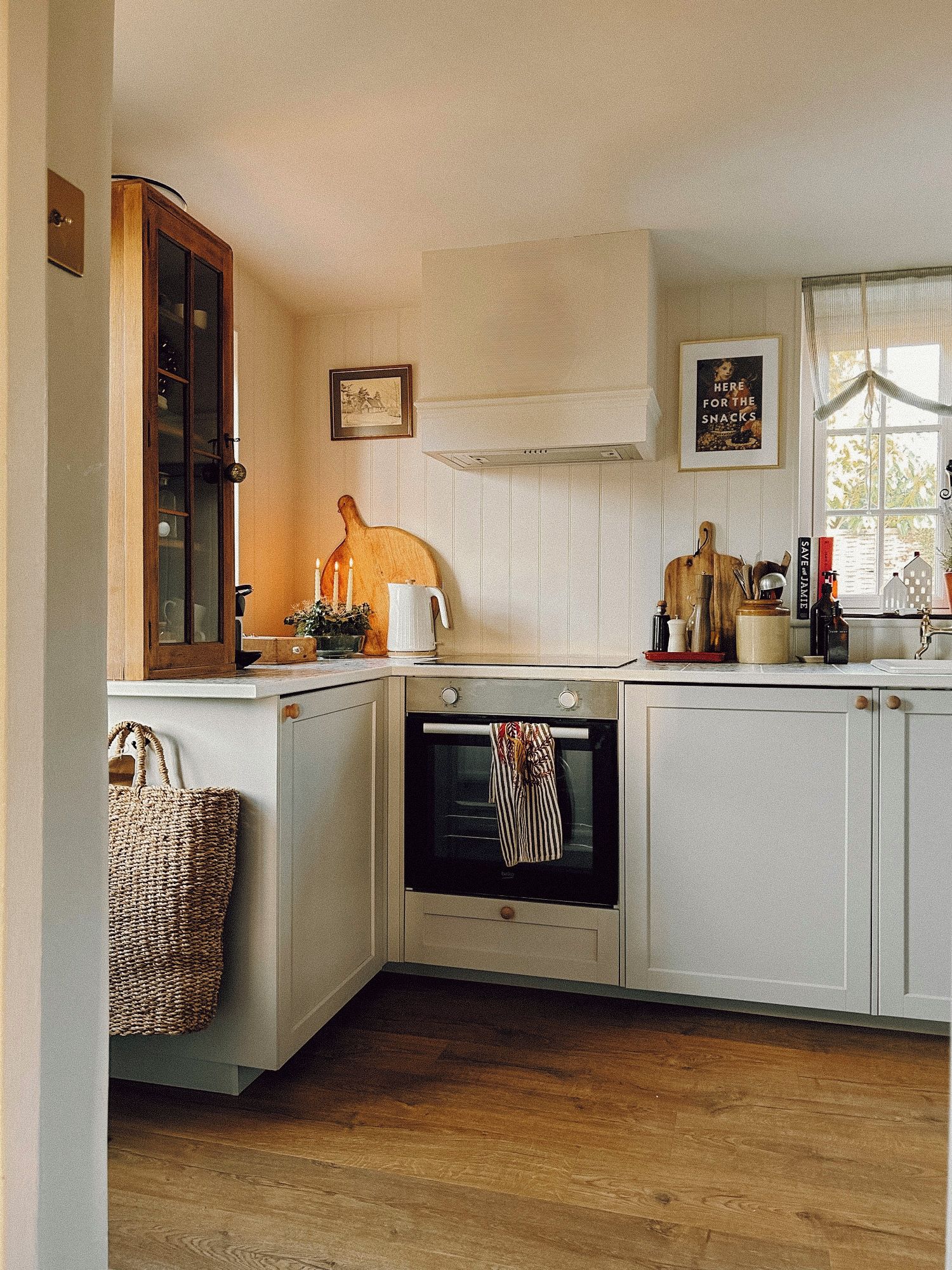 A kitchen with a built-in oven, a wooden cutting board, and a basket.