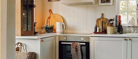 A kitchen with a built-in oven, a wooden cutting board, and a basket.