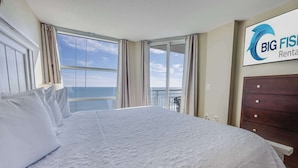 Una habitación de hotel con una cama grande, vista al océano y un cartel de Big Fish Rental.