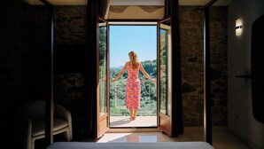 Una stanza con un letto, una sedia e un'ampia porta in vetro che si apre su una vista panoramica.
