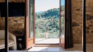 Una camera d'albergo con un letto, una televisione e vista su un paesaggio montano.