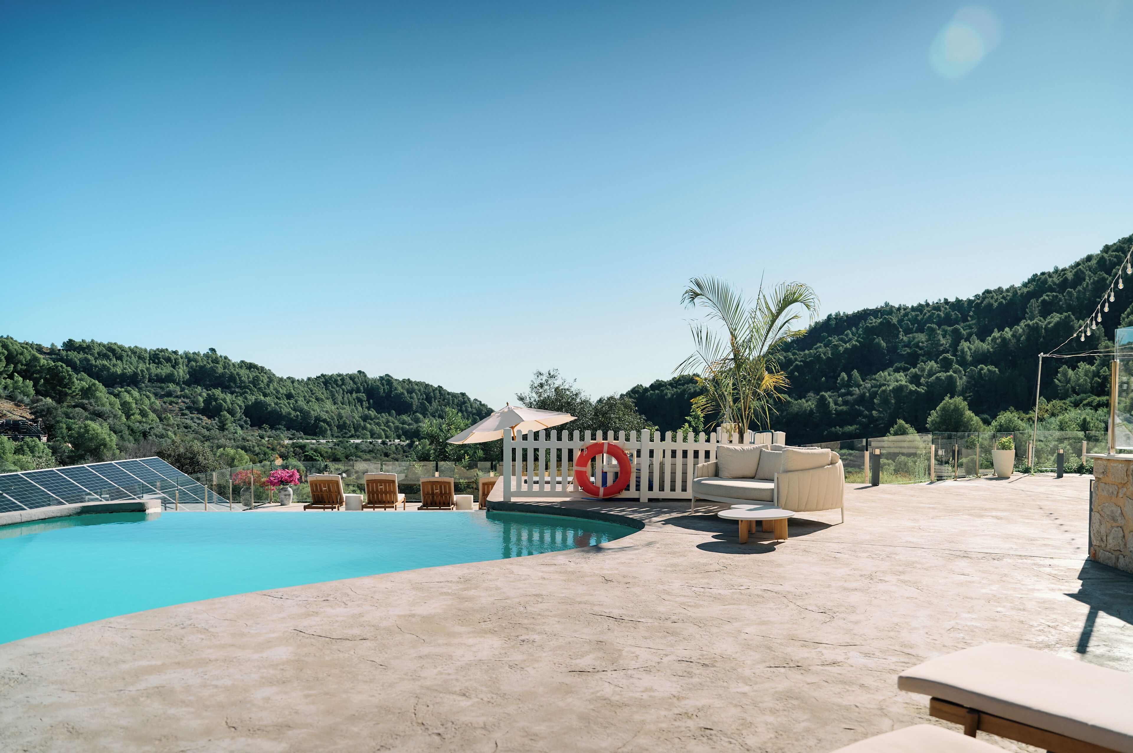 Una piscina con valla blanca, sillas de descanso y un flotador.