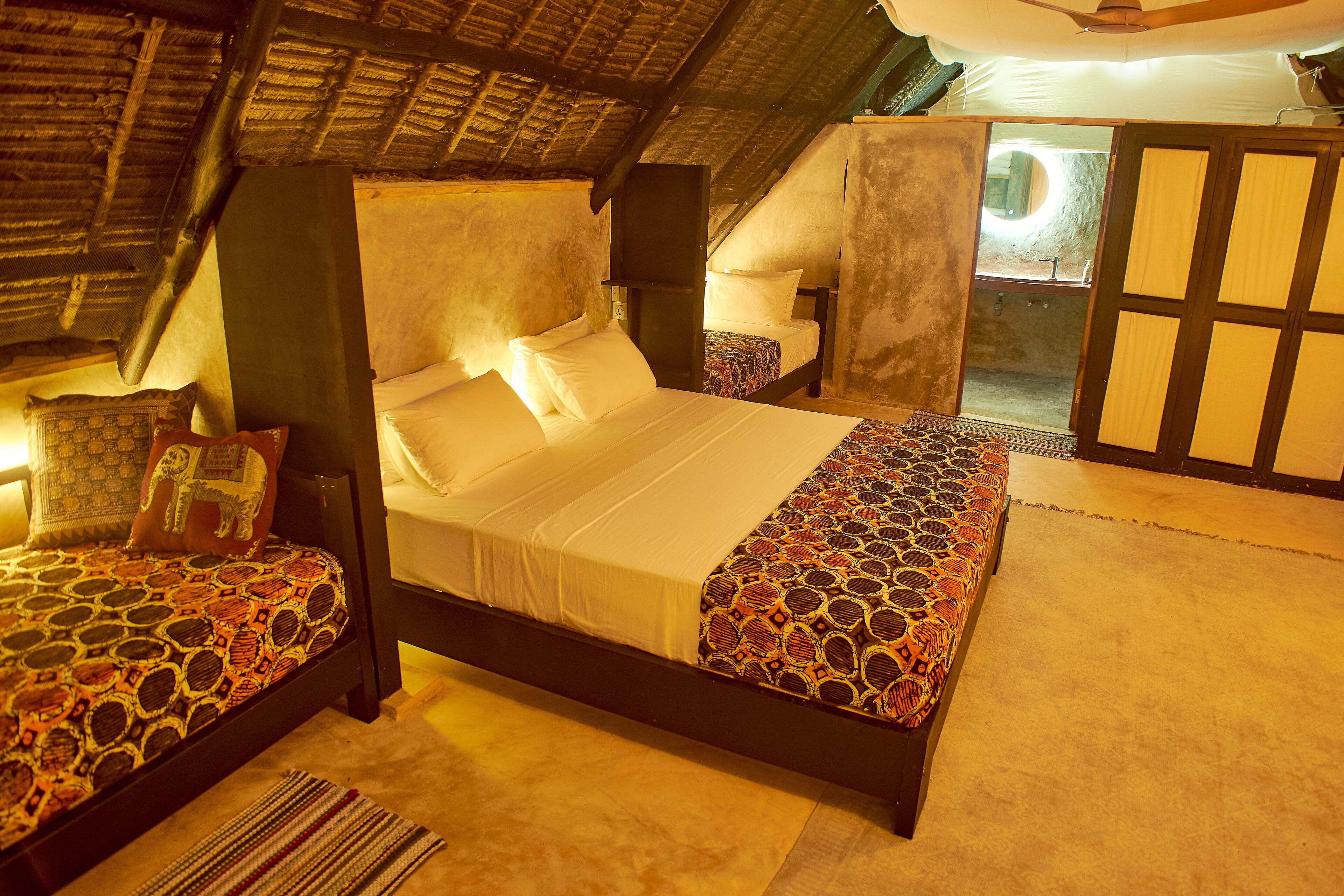 Une chambre avec un grand lit, deux tables de chevet et une petite fenêtre.