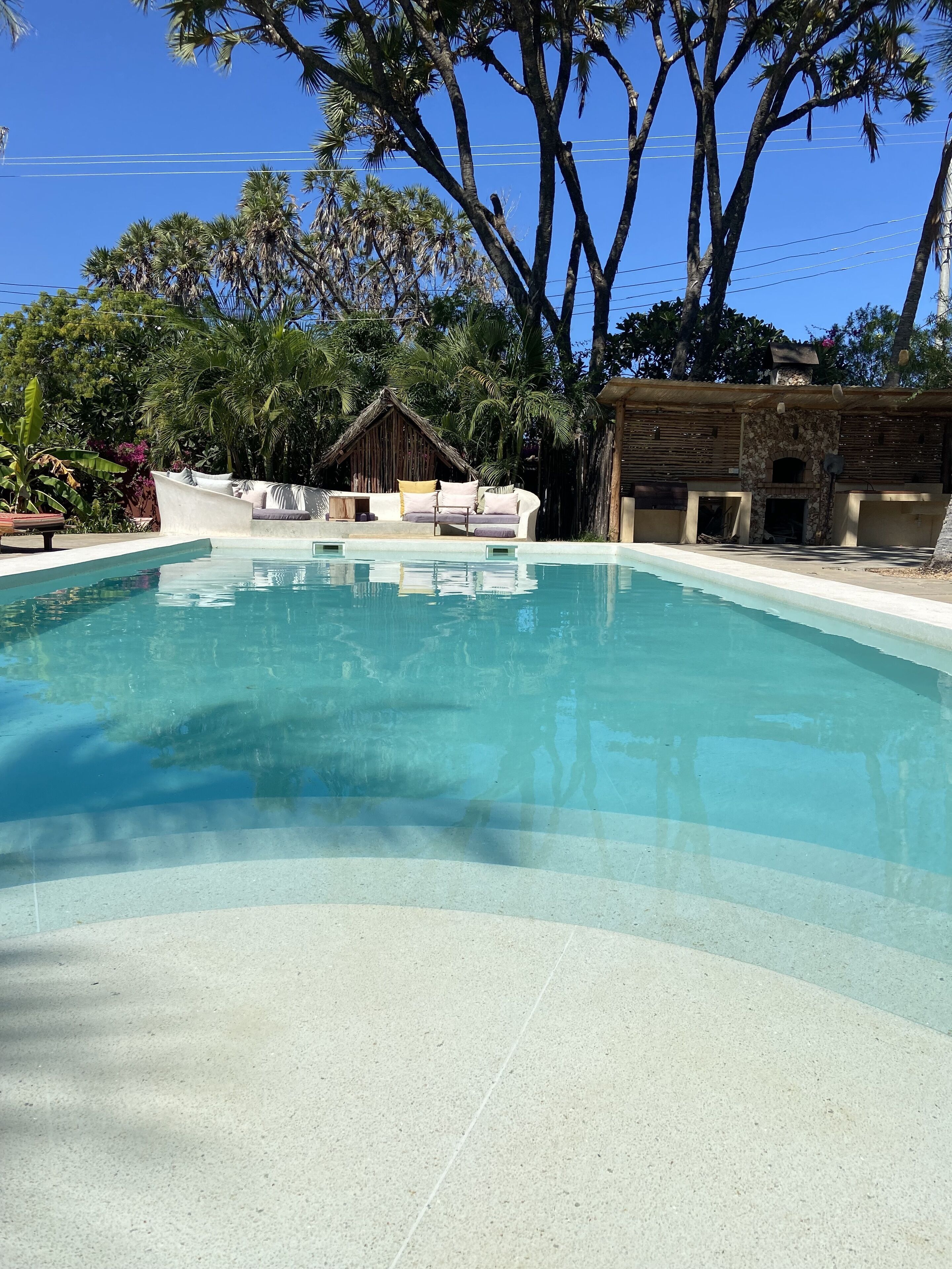 Une piscine aux eaux cristallines, avec un espace de détente et une structure en pierre en arrière-plan.