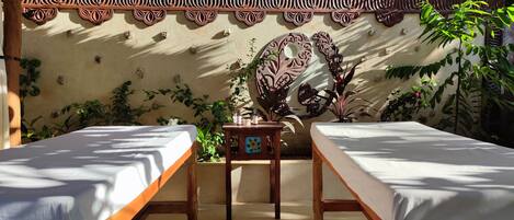 A room with two beds, a decorative wall, and potted plants.