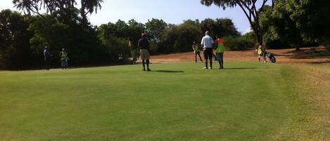 A golf course with players and spectators.