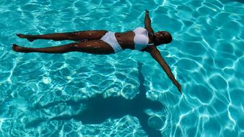 A person floating in a clear blue pool.