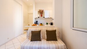 A small, compact room with a kitchenette, a striped sofa, and a window. - LE FLORIDA AP4340 By Riviera Holiday Homes (Villefranche-sur-Mer)