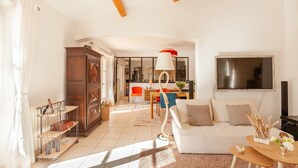A spacious living room with a white sofa, a wooden cabinet, and a dining area with a table and chairs. - Comfortable villa 10 minutes from the beach (La Garde)