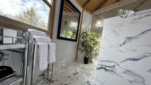 A bathroom with a marble floor, a large mirror, a potted plant, and a towel rack.