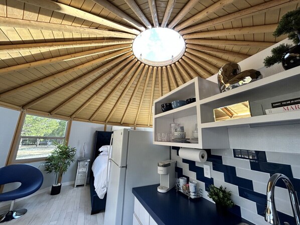 A modern kitchen with a wooden ceiling, a built-in sink, and a window overlooking a garden.
