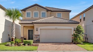 A two-story house with a beige facade, a tiled roof, and a garage. - Beautiful House With First Class Amenities on Solterra Resort, Orlando House 6156 (Davenport)