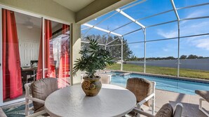 Un patio techado con una piscina, mobiliario exterior y una planta en maceta.