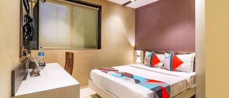 A modern hotel room with a large bed, a desk, and a projector screen.