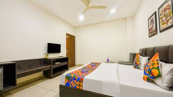 A hotel room with a bed, a TV, a desk, and a ceiling fan.