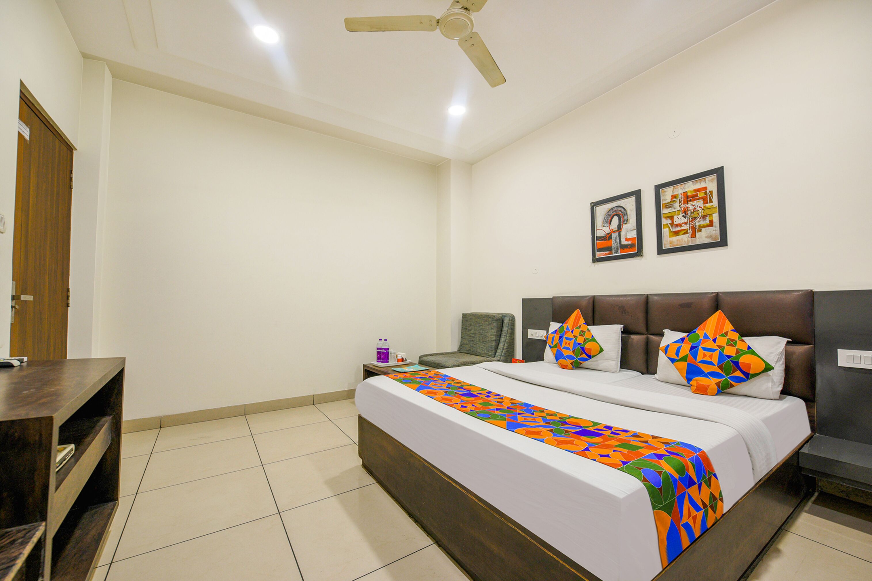 A bedroom with a bed, a nightstand, a chair, a desk, and a ceiling fan.
