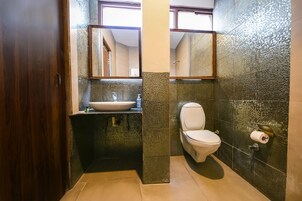 Un baño con puerta de madera, un lavabo, un inodoro y un espejo.