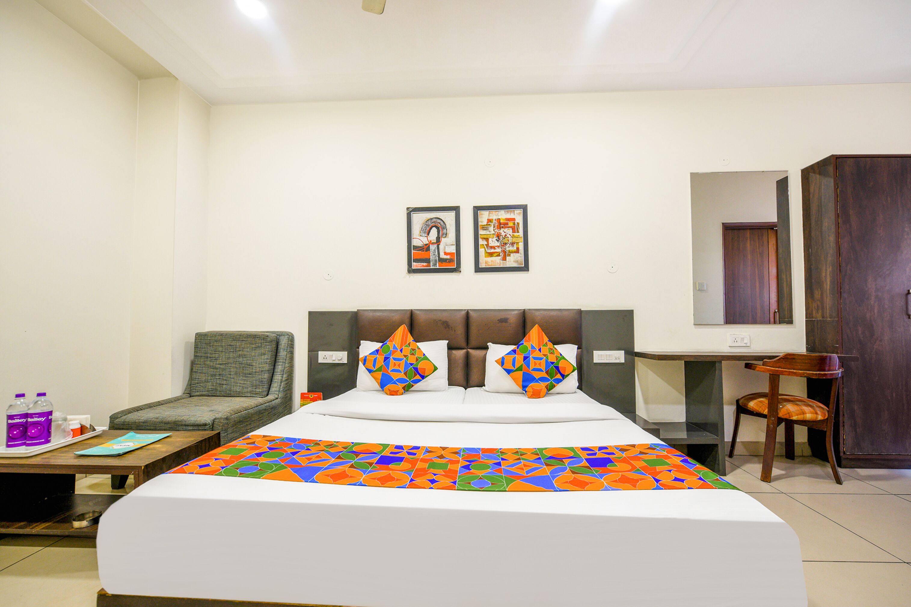 A hotel room with a bed, a chair, a desk, and a wardrobe.