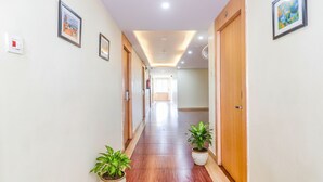 A hallway with wooden doors, framed pictures on the walls, and potted plants.