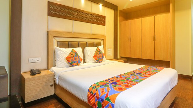 A hotel room with a large bed, wooden headboard, two bedside tables, and a wardrobe.