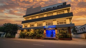 A modern hotel with a flat roof, a prominent 'fabHOTELS' sign, and a well-lit entrance.