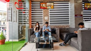 A modern indoor seating area with a glass partition, a coffee table, and a sofa. - Fabhotel Rotano Suites (Bengaluru)