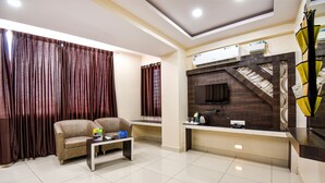 A modern living room with a sofa, coffee table, and a flat-screen TV mounted on a dark wood panel. - Fabhotel Rotano Suites (Bengaluru)