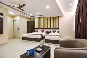 A hotel room with two beds, a ceiling fan, a TV, a coffee table, and a wardrobe. - FabHotel Rotano Suites (Bengaluru)