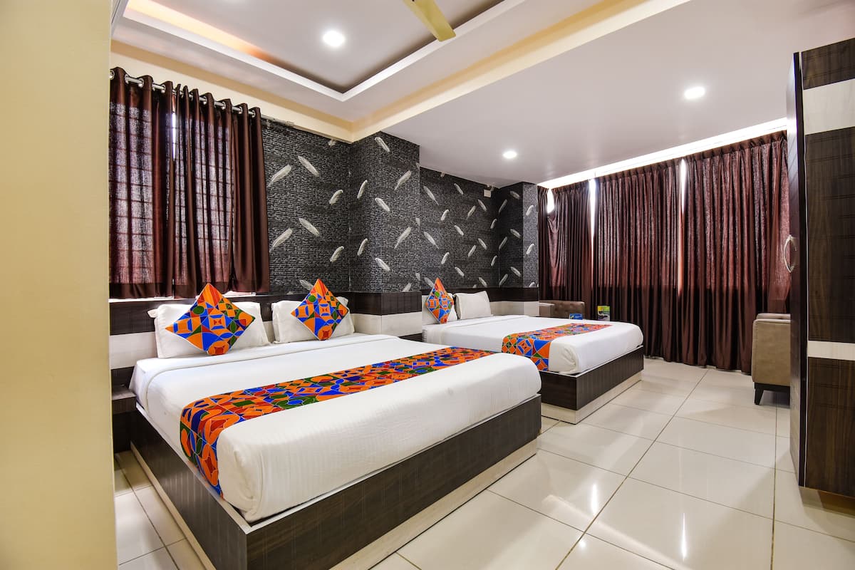Habitación de hotel con dos camas, un ventanal grande con cortinas, un papel tapiz estampado y un diseño moderno en el techo.