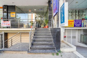 A hotel entrance with a staircase leading to the lobby, a signboard for 'Fabo Hotels', and a 'Supreme' store nearby. - Fabhotel Rove Inn & Suites (Bengaluru)