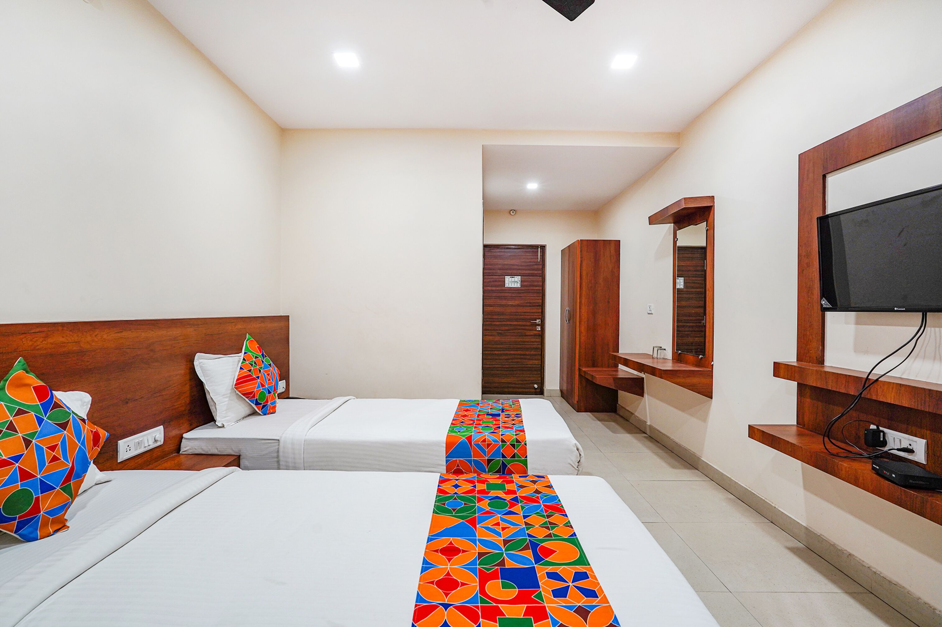 A hotel room with two beds, a TV, and a wooden headboard.
