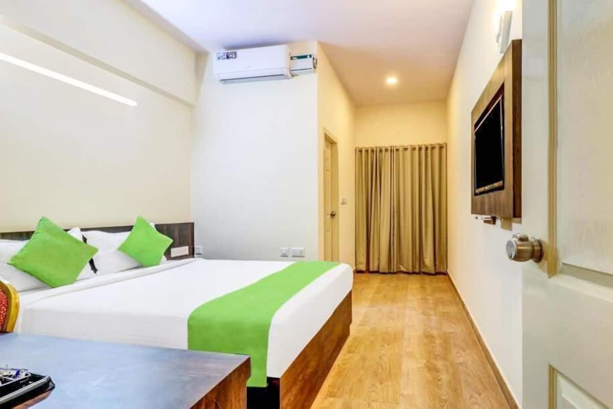 A hotel room with a bed, a TV, a desk, and a curtain.