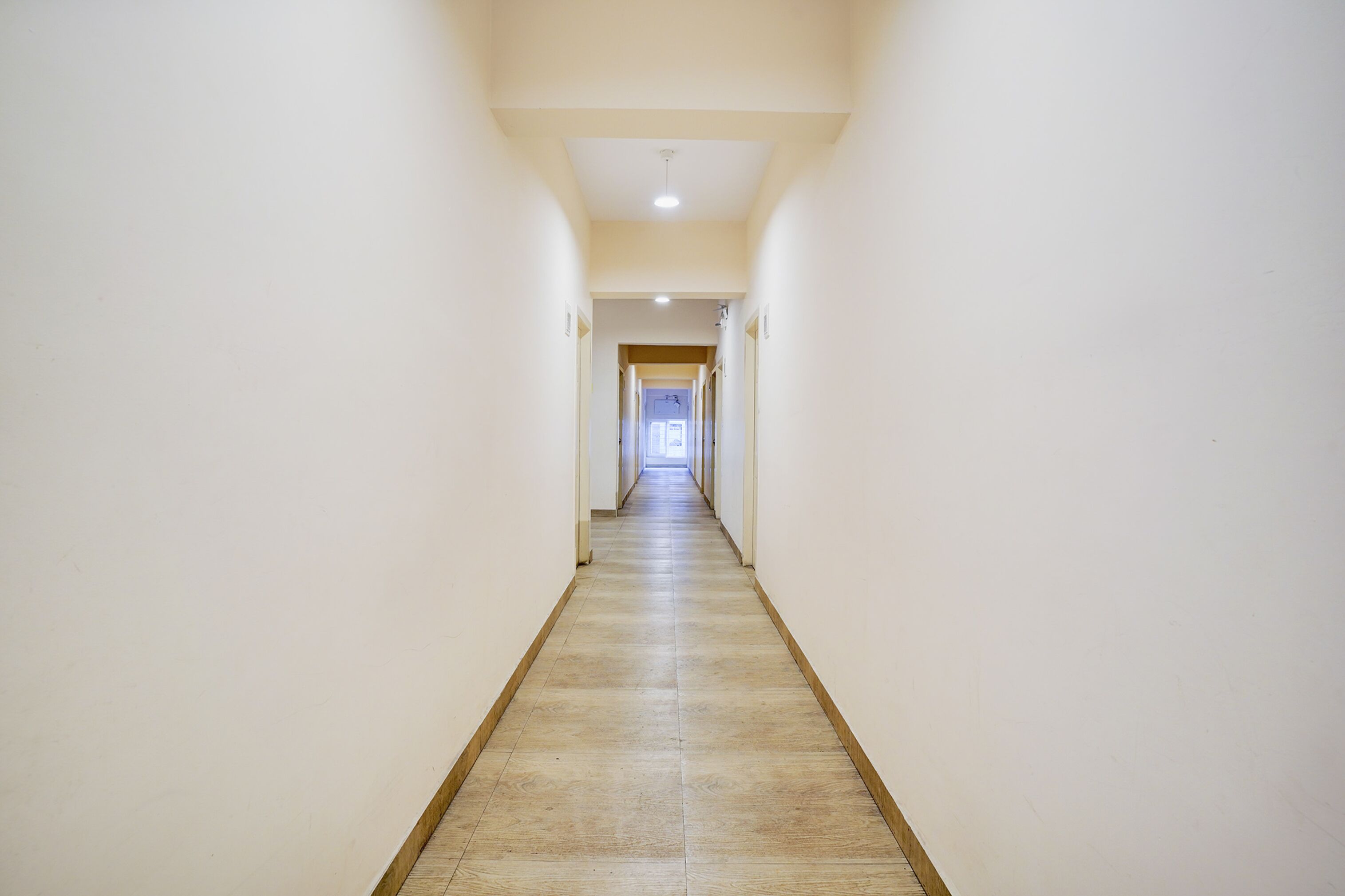 A long, narrow hallway with light-colored walls and a wooden floor.